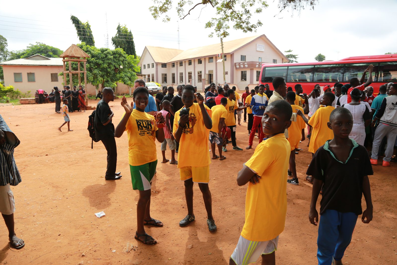 A crowd of runners in yellow shirts gathering near the bus