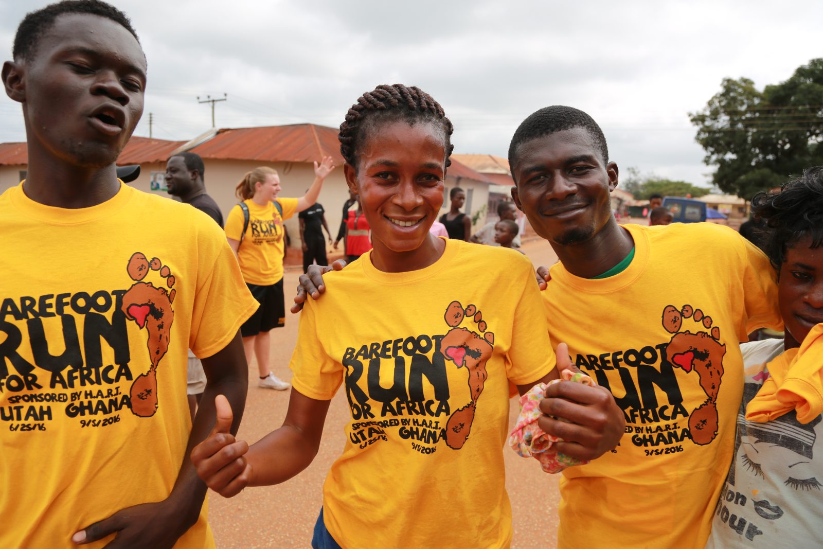 Three runners in race shirts giving thumbs up on the road