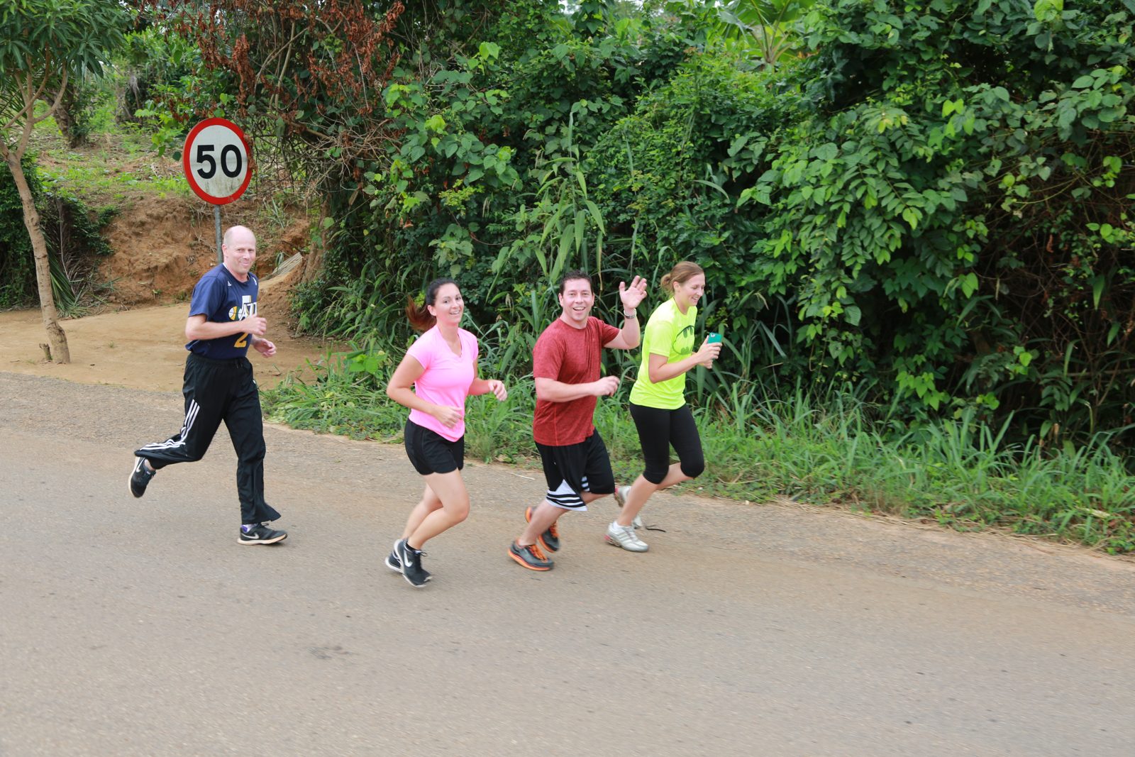 Four volunteers running the road course past the speed limit sign