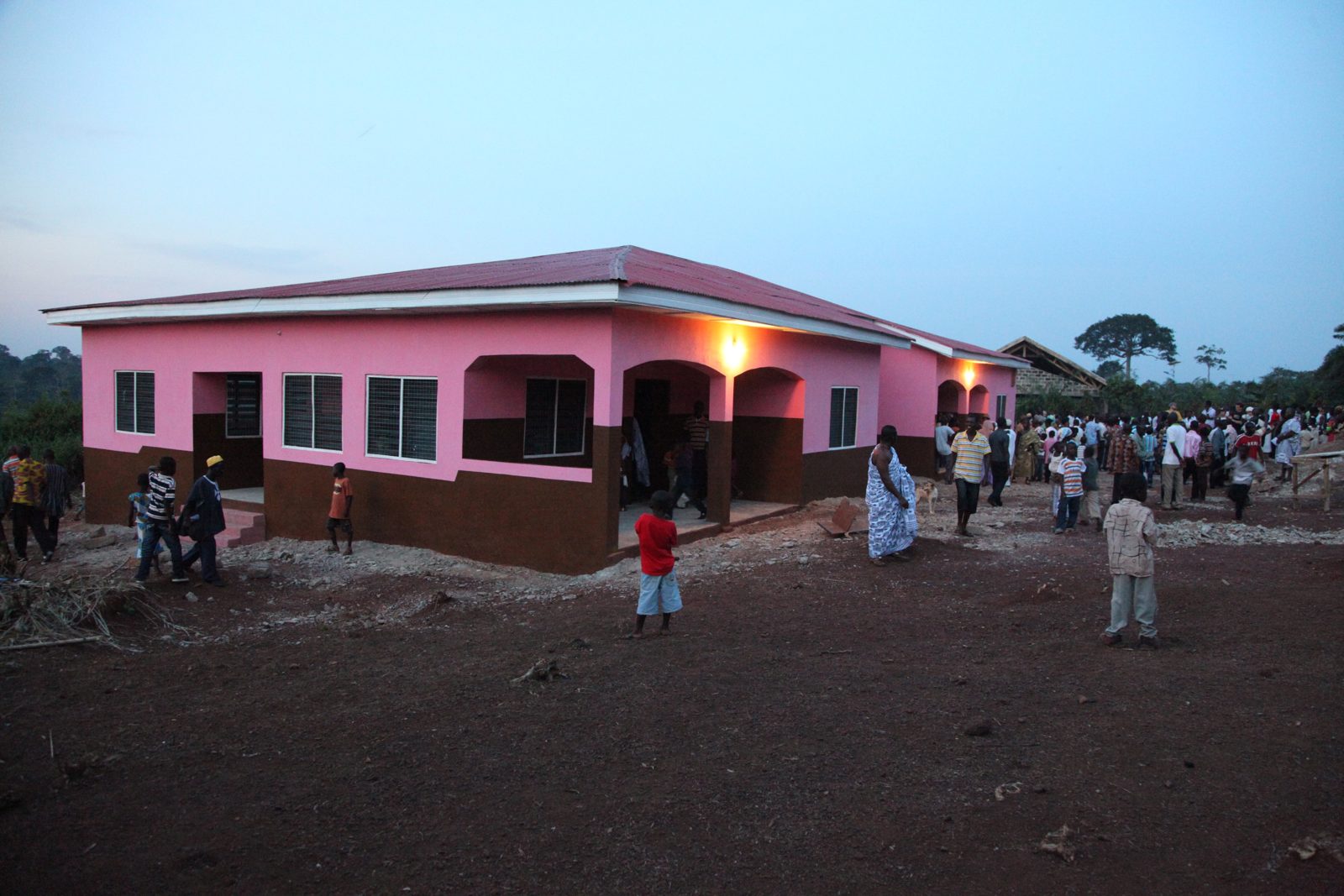 The newly built Beposo clinic at dusk with neighbors gathered outside