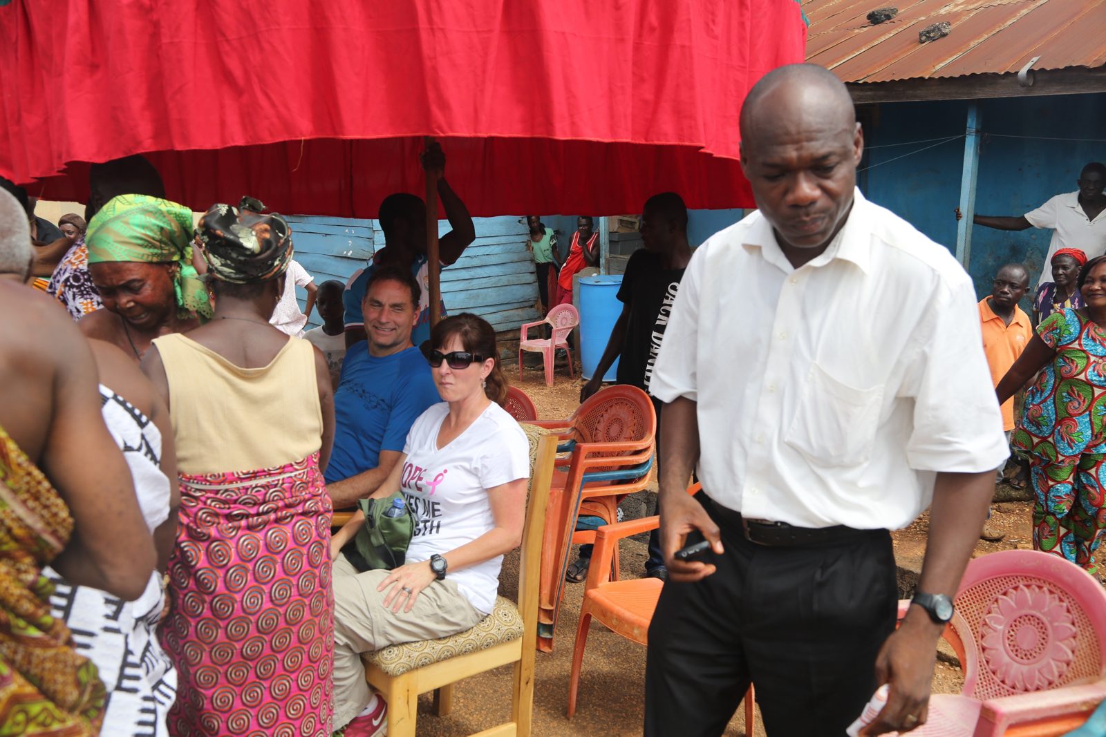 Community members and volunteers seated together at a durbar under bright canopies