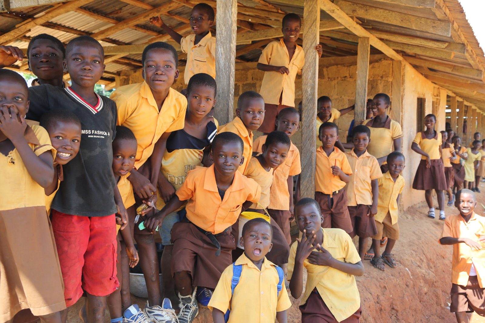 Schoolchildren in uniform smiling under a covered walkway